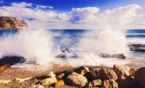 Panoramic view of sea waves splashing on rocks