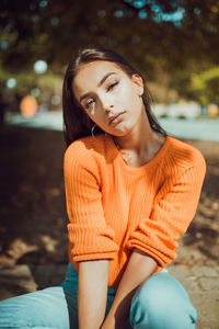 Young woman looking away while sitting outdoors