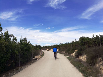 Rear view of man riding motorcycle on road against sky