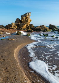 Rock formation on beach against sky