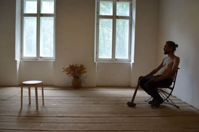 Full length of man sitting on chair at home