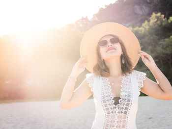 Young woman wearing sunglasses standing against waterfall