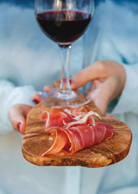 Close-up of wine glass and prosciutto on wooden serving board