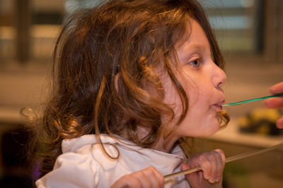 Close-up of girl with spoon in mouth at restaurant