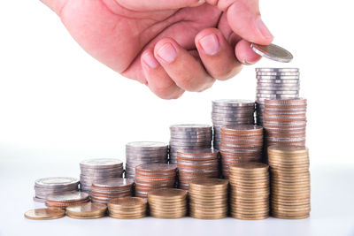 Cropped hand stacking coins on white background