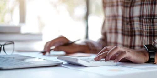 Midsection of woman using laptop on table