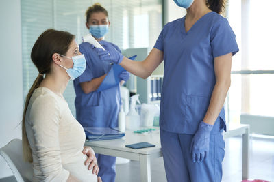 Midsection of female doctor checking temperature patent in clinic