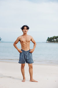 Shirtless man standing at beach