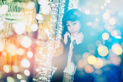 Portrait of young woman looking at illuminated lights