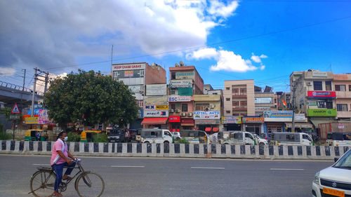 Bicycles on road by buildings in city against sky