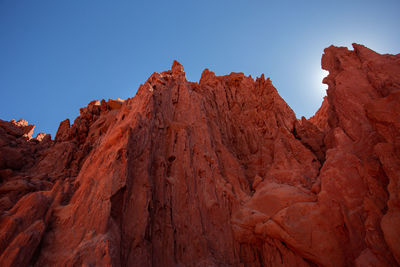 Low angle view of rocky mountains against clear blue sky