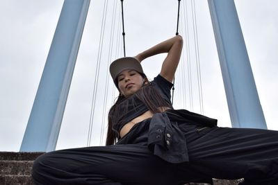 Low angle view of female hip hop dancer against bridge