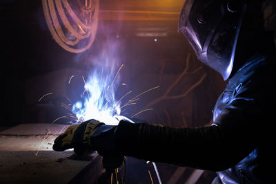 Persona working with an electric welding machine. a man in safety glasses and a leather jacket cooks