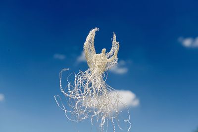 Low angle view of animal representation against blue sky