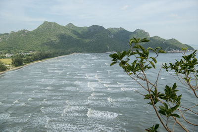 Scenic view of sea by mountain against sky