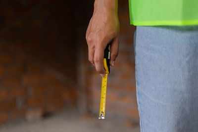 Midsection of man holding tape measure