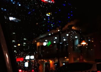 Illuminated city street seen through wet window