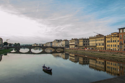 Bridge over river in city against sky