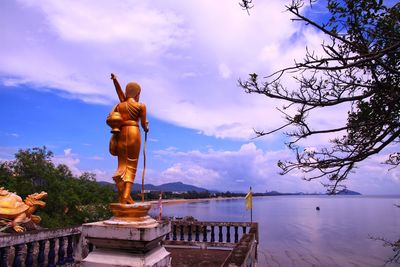 Statue by trees against sky during sunset