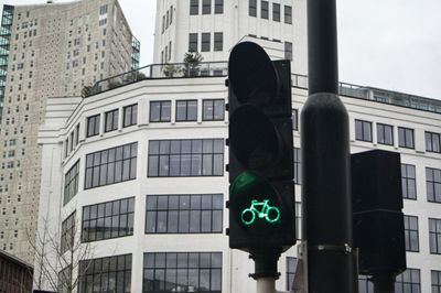Low angle view of road signal against buildings in city