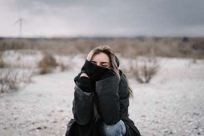 Portrait of woman standing on sand on the beach during winter