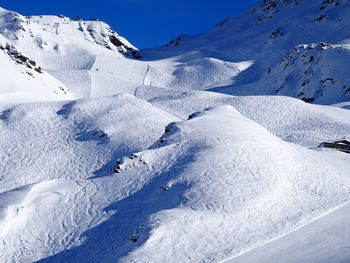 Scenic view of snowcapped mountains against blue sky on sunny day