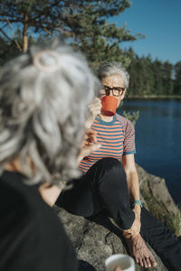 Two senior women sitting on rock at lakeshore