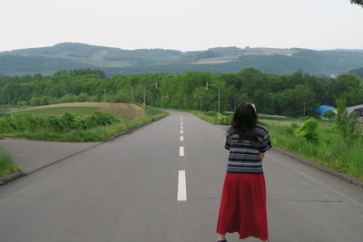 Rear view of woman standing on road