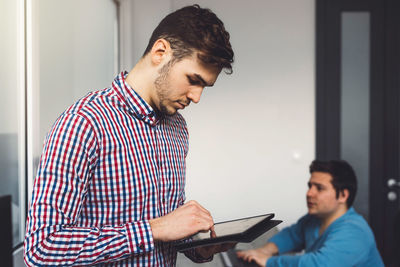 Side view of man using mobile phone while standing in office