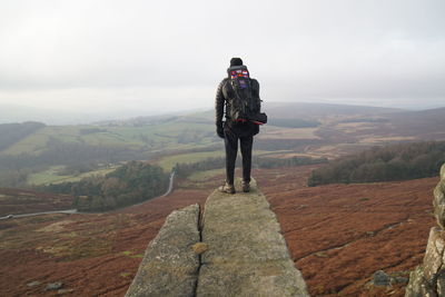 Rear view of man standing on mountain against sky