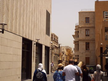 Rear view of people on street against buildings in city