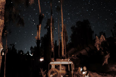 Panoramic shot of illuminated carousel against sky at night
