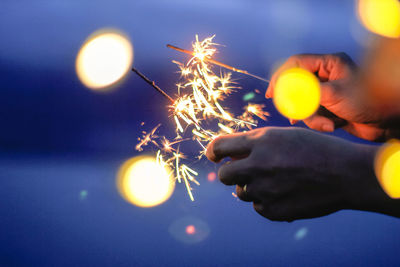 Low angle view of hand holding sparkler at night