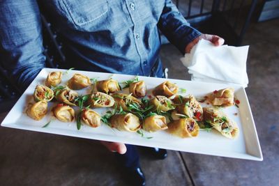 High angle view of man holding tray of fried wontons