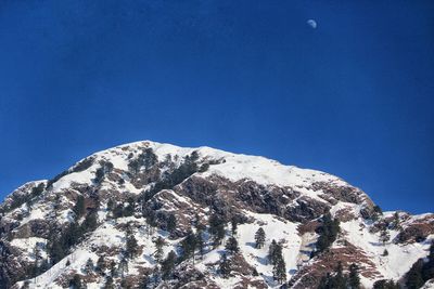 Low angle view of snowcapped mountain against blue sky