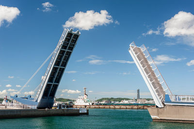 Low angle view of cranes in city against sky