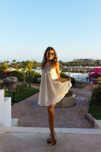 Full length of young woman standing against clear sky