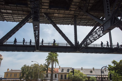 Low angle view of people walking on bridge in city