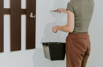 A young girl paints a wall with a brush.