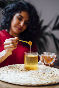 Brunette woman sweetening a tea with honey