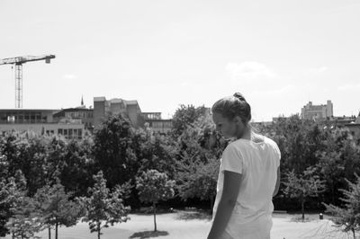 Young woman standing by tree against sky