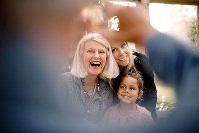 Senior man photographing happy family at dining table during lunch