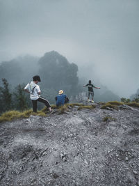 People on cliff against sky during foggy weather