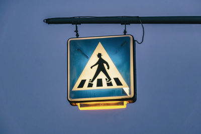 Low angle view of road sign against clear blue sky