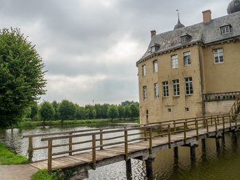 Bridge over river by buildings against sky