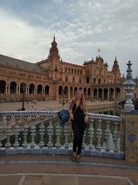 Full length of woman standing on bridge in city against sky