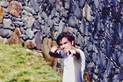 Portrait of young man gesturing while standing on field