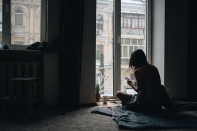 Woman reading book while sitting on floor at home