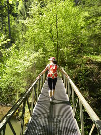 Man walking on footbridge in forest