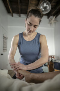 A female massage therapist massages her patient's foot